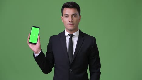 Young-handsome-Hispanic-businessman-against-green-background