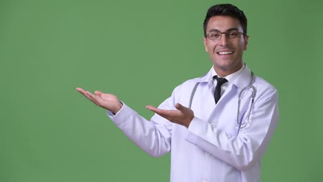 Young-handsome-Hispanic-man-doctor-against-green-background