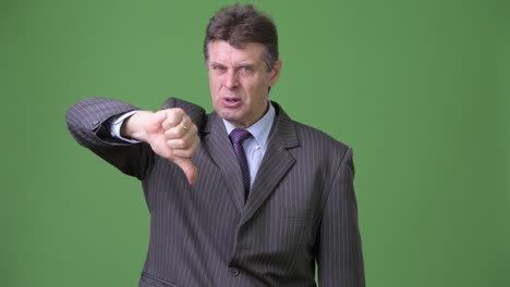 Mature-handsome-businessman-against-green-background