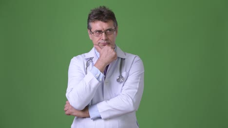 Mature-handsome-man-doctor-against-green-background