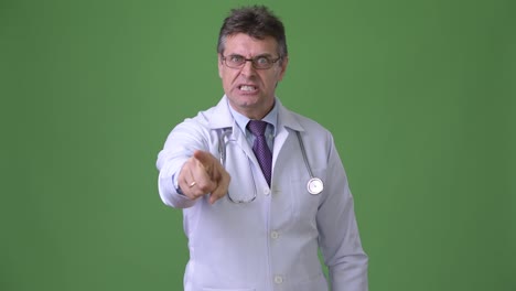 Mature-handsome-man-doctor-against-green-background