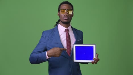 Young-handsome-African-businessman-with-dreadlocks-against-green-background