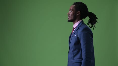 Young-handsome-African-businessman-with-dreadlocks-against-green-background