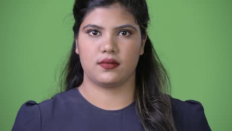 Young-overweight-beautiful-Indian-businesswoman-against-green-background