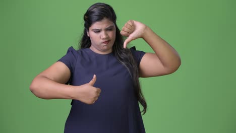 Young-overweight-beautiful-Indian-businesswoman-against-green-background