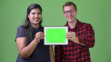 Young-multi-ethnic-business-couple-together-against-green-background