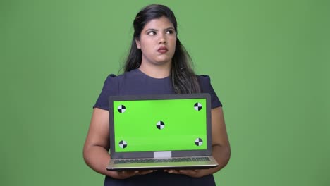 Young-overweight-beautiful-Indian-businesswoman-against-green-background