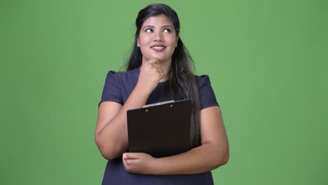 Young-overweight-beautiful-Indian-businesswoman-against-green-background