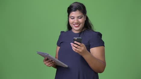 Young-overweight-beautiful-Indian-businesswoman-against-green-background
