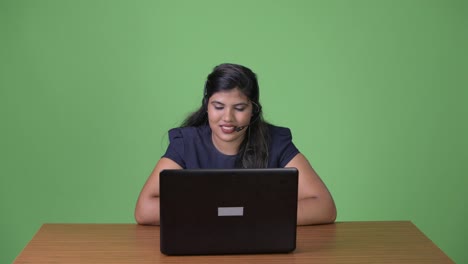 Young-overweight-beautiful-Indian-businesswoman-against-green-background