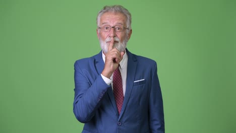 Handsome-senior-bearded-businessman-against-green-background