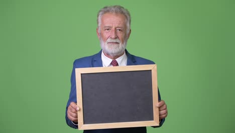 Handsome-senior-bearded-businessman-against-green-background