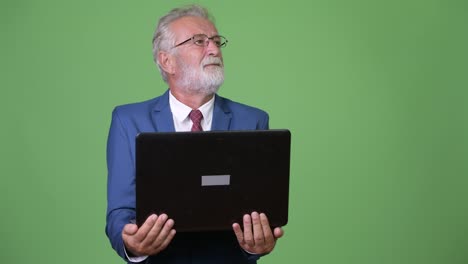 Handsome-senior-bearded-businessman-against-green-background