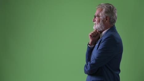 Handsome-senior-bearded-businessman-against-green-background