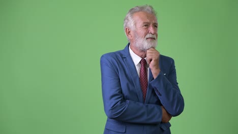 Handsome-senior-bearded-businessman-against-green-background