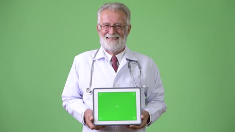 Handsome-senior-bearded-man-doctor-against-green-background