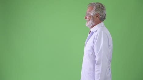 Handsome-senior-bearded-man-doctor-against-green-background