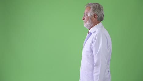 Handsome-senior-bearded-man-doctor-against-green-background