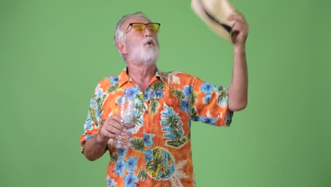 Handsome-senior-bearded-tourist-man-ready-for-vacation-against-green-background