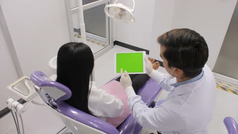 Dentist-explaining-procedure-to-patient-from-greenscreen-tablet