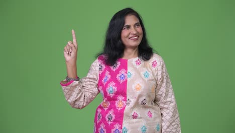 Mature-happy-beautiful-Indian-woman-thinking-while-pointing-finger-up