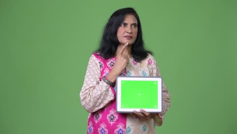 Mature-beautiful-Indian-woman-thinking-while-showing-digital-tablet