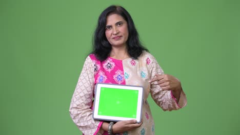 Mature-beautiful-Indian-woman-showing-digital-tablet-and-pointing-finger