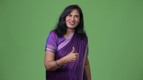 Mature-happy-beautiful-Indian-woman-giving-thumbs-up-while-wearing-Sari-traditional-clothes