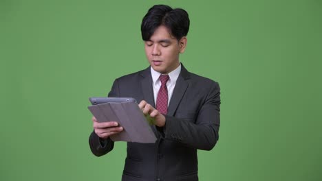 Young-handsome-Asian-businessman-using-digital-tablet