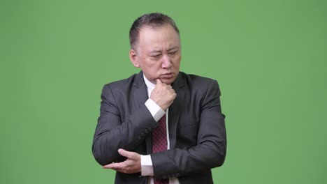 Mature-stressed-Japanese-businessman-looking-down-while-thinking