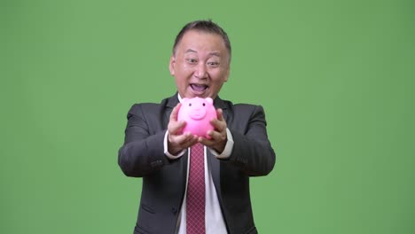 Reife-japanischer-Geschäftsmann-hält-Sparschwein