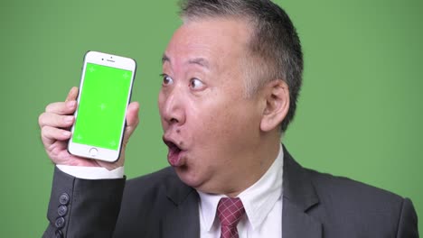 Mature-Japanese-businessman-showing-phone-to-camera