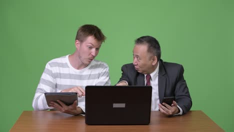 Mature-Japanese-businessman-and-young-Scandinavian-businessman-working-together