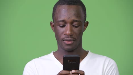 Young-African-man-using-phone-against-green-background