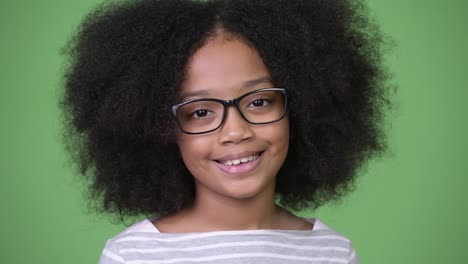 Joven-feliz-niña-africana-con-el-pelo-Afro-sonriendo-contra-el-fondo-verde