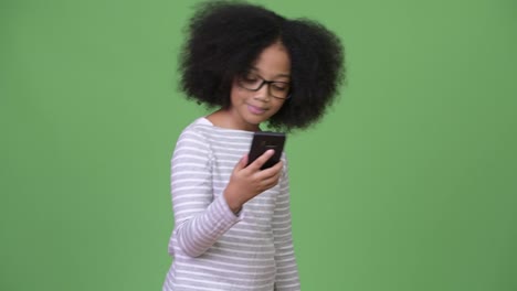 Joven-linda-chica-africana-con-el-pelo-Afro-mediante-teléfono-y-celebrando