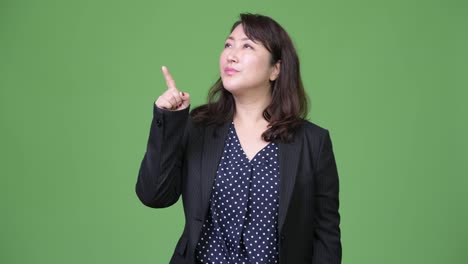 Mature-beautiful-Asian-businesswoman-thinking-while-pointing-finger-up