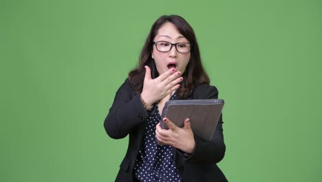 Mature-beautiful-Asian-businesswoman-looking-shocked-while-using-digital-tablet