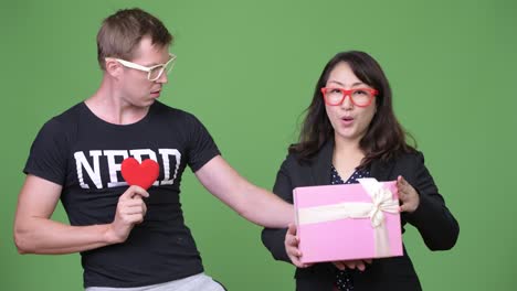 Mature-Asian-businesswoman-and-young-Scandinavian-nerd-man-celebrating-Valentine's-day-together