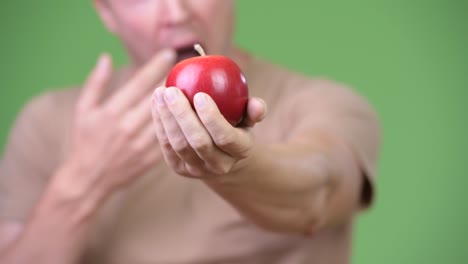 Young-handsome-Scandinavian-man-looking-shocked-while-holding-apple