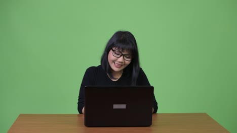 Beautiful-Asian-businesswoman-thinking-while-using-laptop