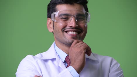 Young-handsome-Persian-man-doctor-wearing-protective-glasses-thinking