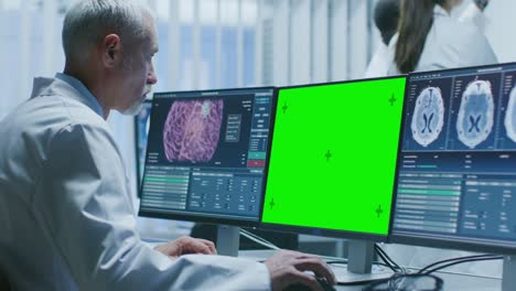 Senior-Medical-Research-Scientist-Working-with-Brain-Scans-on-His-Personal-Computer-Showing-Green-Mock-up-Screen.-Modern-Laboratory-Working-on-Neurophysiology,-Science,--Neuropharmacology.-Understanding-Human-Brain.