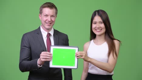 Multi-ethnic-business-couple-showing-digital-tablet-together