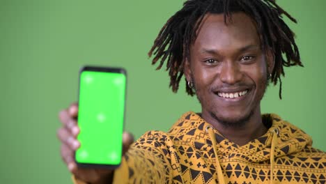 Young-happy-handsome-African-man-smiling-while-showing-phone