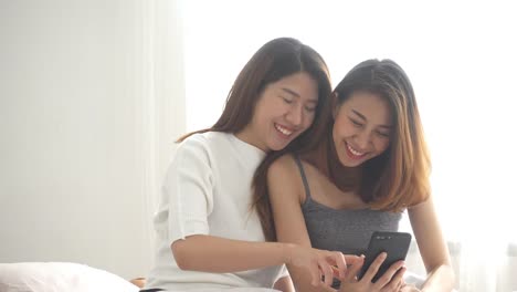 Beautiful-young-asian-women-LGBT-lesbian-happy-couple-sitting-on-bed-hug-and-using-phone-together-bedroom-at-home.-LGBT-lesbian-couple-together-indoors-concept.-Spending-nice-time-at-home.