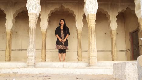 Indian-woman-greets-namaste-welcomes-invites-joy-warm-temple-ancient-Indian-Hindu-traditional-architecture--black-hair-big-smile-happy-guest-home-interior-static-copy-space-wide-shot-lock-down-frame