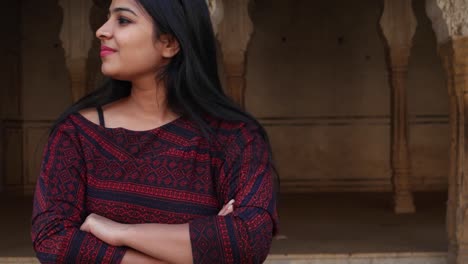 Handheld-shot-of-woman-pissed-angry-bad-mood-smart-watch-late-nods-surprised-smiles-joke-kidding-joy-hands-on-face--looks-at-camera-in-old-ancient-Hindu-temple-facade-complex-holy-city-move-to-frame