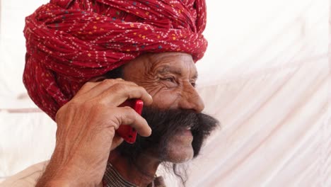 Mano-hombre-mayor-de-Rajasthani-en-una-conversación-móvil-del-teléfono-celular-inteligente