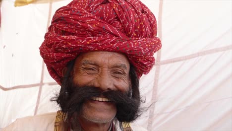 Close-up-Smiling-man-from-Rajasthan-salutes-with-big-moustache-wearing-a-red-turban-and-tradition-dress